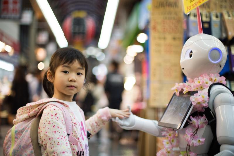 Una niña saluda a un robot. Foto: Unsplash